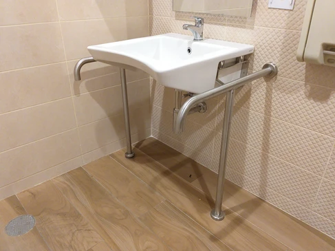 Salle de bain adaptée avec lavabo suspendu blanc équipé de barres d'appui en acier inoxydable